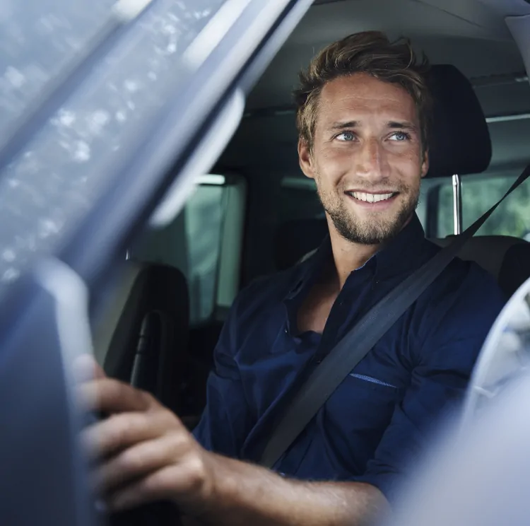 A learner driver at the wheel, seatbelt on, looking to the side